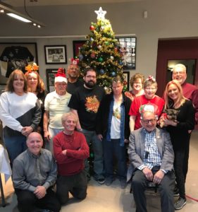 Staff gathers in front of a Christmas tree in the lobby
